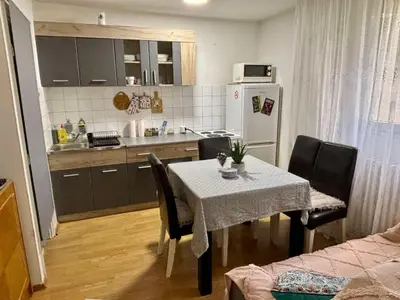 a kitchen with a table and chairs and a kitchen with a refrigerator at Apartman KEJ Smederevo in Smederevo