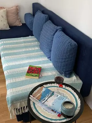 a blue couch with a table with a glass of wine at Apartman KEJ Smederevo in Smederevo