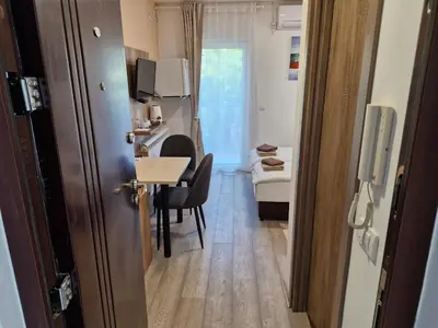 a small room with a small table and a room with a kitchen at Apartman New in Belgrade