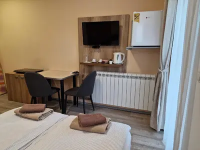 a room with two beds and a table and a tv at Apartman New in Belgrade