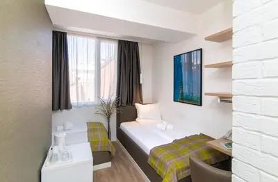a hotel room with two beds and a desk at Belgrade Inn Garni Hotel in Belgrade