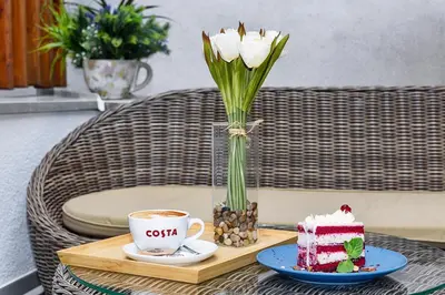 a table with a vase of flowers and a piece of cake at Belgrade Inn Garni Hotel in Belgrade