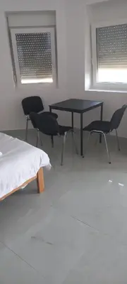a room with a table and chairs and two windows at All SEASON in Beograd