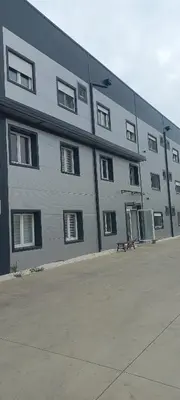 a large gray building with a bench in front of it at All SEASON in Beograd