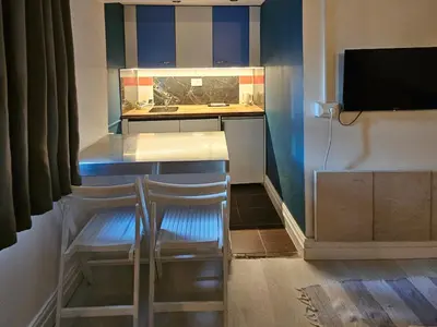 a kitchen with two chairs at a counter with a television at Appartamento con ingresso privato e vista giardino in Belgrade