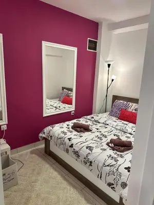 a bedroom with a purple wall with a bed and a mirror at Cozy studio in Belgrade in Belgrade