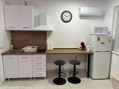 a kitchen with a counter with two stools and a refrigerator at Cozy studio in Belgrade in Belgrade