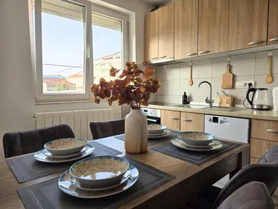 a kitchen with a table with plates and flowers on it at Airport 2BR Suite Filip in Beograd