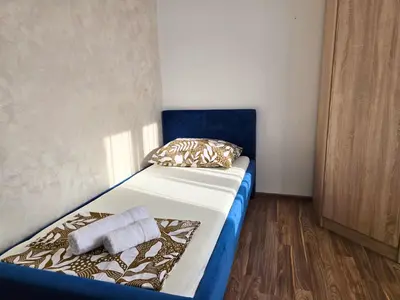 a small bedroom with a bed with a blue headboard at Airport 2BR Suite Filip in Beograd
