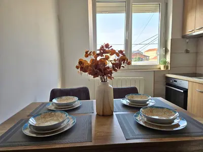 a dining room table with four dishes and a vase with flowers at Airport 2BR Suite Filip in Beograd
