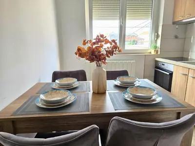 a dining room table with dishes and a vase of flowers at Airport 2BR Suite Filip in Beograd