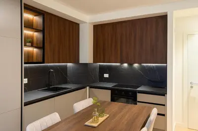 a kitchen with a wooden table and black counter tops at Belgrade Waterfront LuX Sky Residence in Belgrade