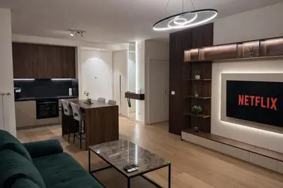 a living room with a green couch and a kitchen at Belgrade Waterfront LuX Sky Residence in Belgrade