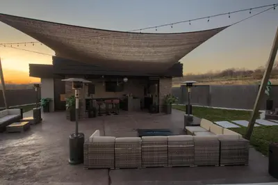 a living area with couches and a patio with the sunset at House California