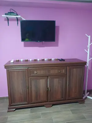 a large wooden cabinet with a flat screen tv on a pink wall at Stan Na Dan Pancevo in Pančevo