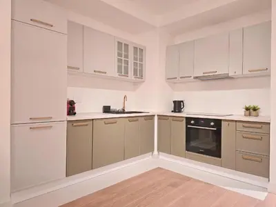 a kitchen with white cabinets and a stove top oven at Eterna Premium Apartment 1 Bedroom in Sajmište