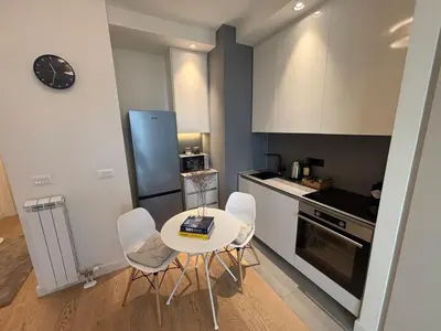 a kitchen with a table and chairs and a clock at NEW! Modern Studio Belgrade Waterfront in Belgrade