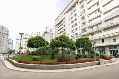 a park with trees and flowers in front of a building at DC Belgrade, modern, super comfy, garage parking in Belgrade
