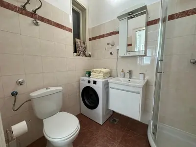 a bathroom with a toilet a sink and a washing machine at Eight Apartment Two Bedroom City Centre Comfort in Belgrade