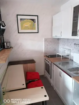 a small kitchen with white cabinets and a red stool at City pioneer Apartmens in Belgrade
