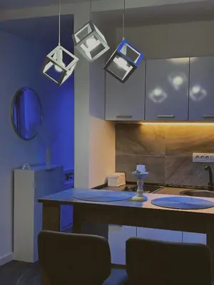 a kitchen with a table with chairs and lights at Honey apartments in Ledine