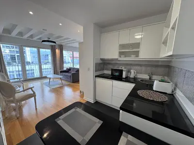 a kitchen with white cabinets and a living room at City View Apartments in Belgrade