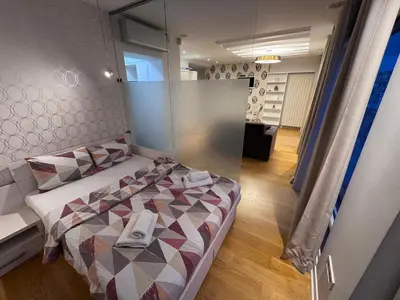 a bedroom with a large bed with a glass wall at City View Apartments in Belgrade