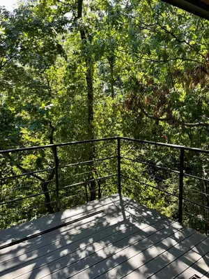 a balcony with a fence and trees in the background at Furo Treehouse in Barajevo
