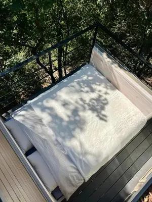 a mattress on a porch with a tree shadow at Furo Treehouse in Barajevo