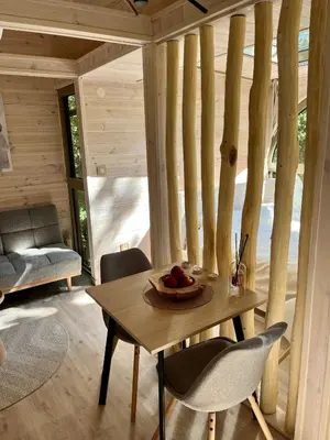 a wooden table and chairs in a room with trees at Furo Treehouse in Barajevo