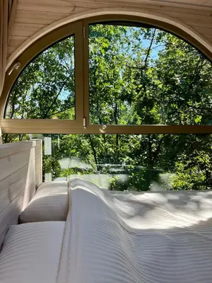 an open window with white beds in front of a window at Furo Treehouse in Barajevo