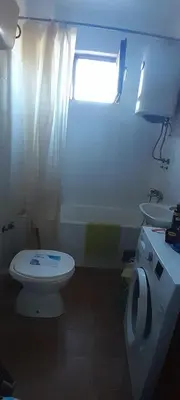 a bathroom with a toilet and a sink and a window at Airport Guesthouse Rooms and Apartmants in Beograd