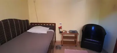 a small bedroom with a bed and a black chair at Airport Guesthouse Rooms and Apartmants in Beograd