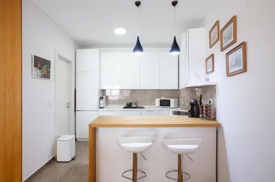 a kitchen with white cabinets and a counter with stools at Central Garden Apartment - Parking & Security in Belgrade