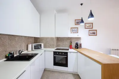 a kitchen with white cabinets and a wooden counter top at Central Garden Apartment - Parking & Security in Belgrade