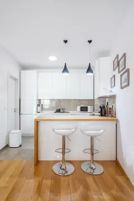 a kitchen with white cabinets and bar stools at Central Garden Apartment - Parking & Security in Belgrade