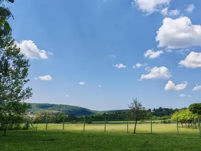 a fence in a field with a blue sky and clouds at ART HOUSE Kosmaj 1 in Sopot