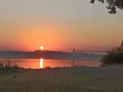 a sunset over a body of water with the sun setting at Katera S in Zemun