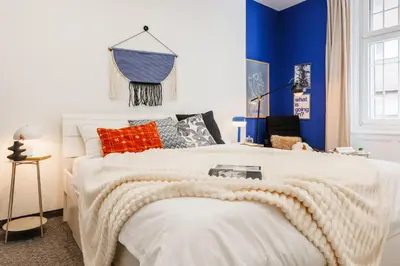 a bedroom with a large white bed with blue walls at Velvet Stay 120m2 with Foosball Old Town in Belgrade