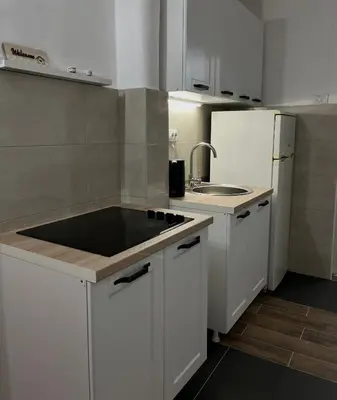 a kitchen with white cabinets and a sink and a refrigerator at msapartman in Surčin