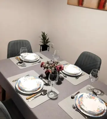 a table with plates and wine glasses on it at msapartman in Surčin