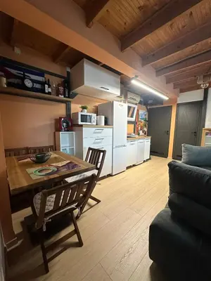 a kitchen and living room with a table and a couch at Unique River Houseboat Stay in Železnička Stanica Senjak