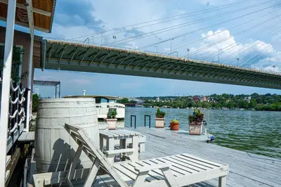 a dock with two chairs and a bridge at Unique River Houseboat Stay in Železnička Stanica Senjak