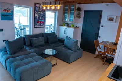 a living room with a blue couch and a table at Unique River Houseboat Stay in Železnička Stanica Senjak