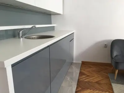 a white kitchen with a sink and a chair at Apartment Silver Pedestrian Zone in Belgrade