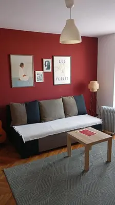 a living room with a couch and a red wall at Mansard Crimson Rhapsody in Belgrade