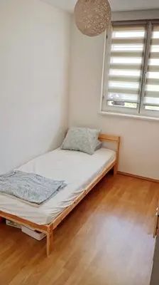 a small bedroom with a bed and two windows at Mansard Crimson Rhapsody in Belgrade