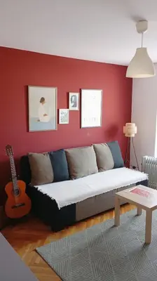 a couch in a living room with a red wall at Mansard Crimson Rhapsody in Belgrade
