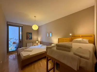a bedroom with two beds and a large window at Downtown family apartment in Belgrade