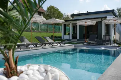 a pool with chairs and umbrellas next to a house at Aeri Nature Concept in Baljevac